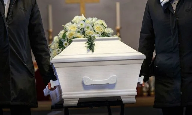 Hvid kiste båret af to personer under begravelse.